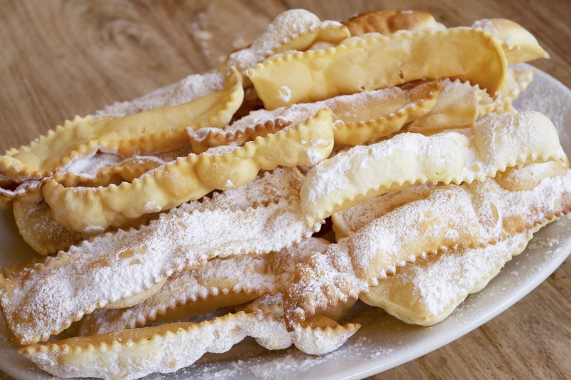 chiacchiere di carnevale in vassoio bianco su tavolo di legno