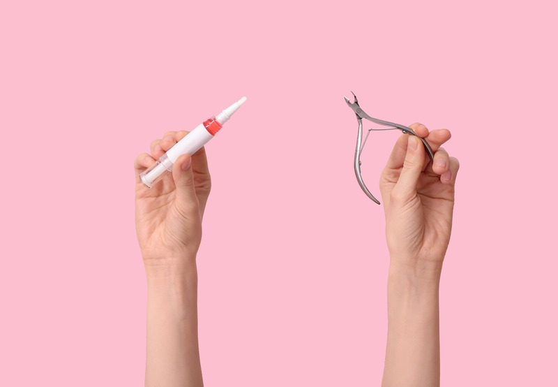 forbice per cuticole e penna con olio per cuticole, sfondo rosa