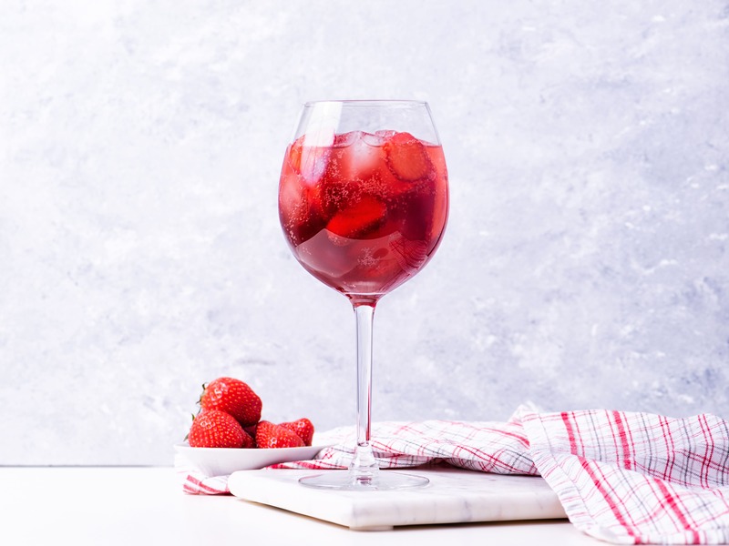 bicchiere di fragole al vino su tagliere di marmo chiaro