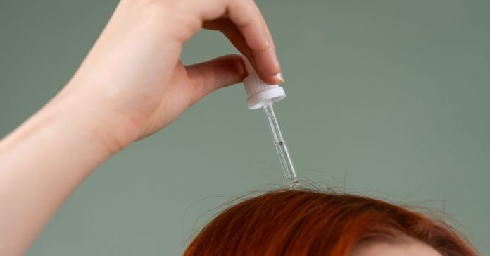 L’antigiallo per capelli è un trattamento pensato per… L’antigiallo per capelli è un trattamento pensato per…: Primo piano di una mano che applica siero per capelli su capelli…