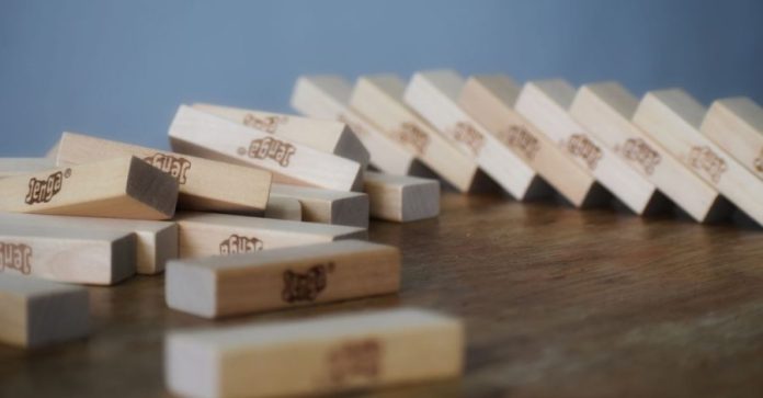 Jenga spiegato bene: dalla torre iniziale alle mosse che fanno perdere: Primo piano di blocchi di Jenga in legno sparsi su…